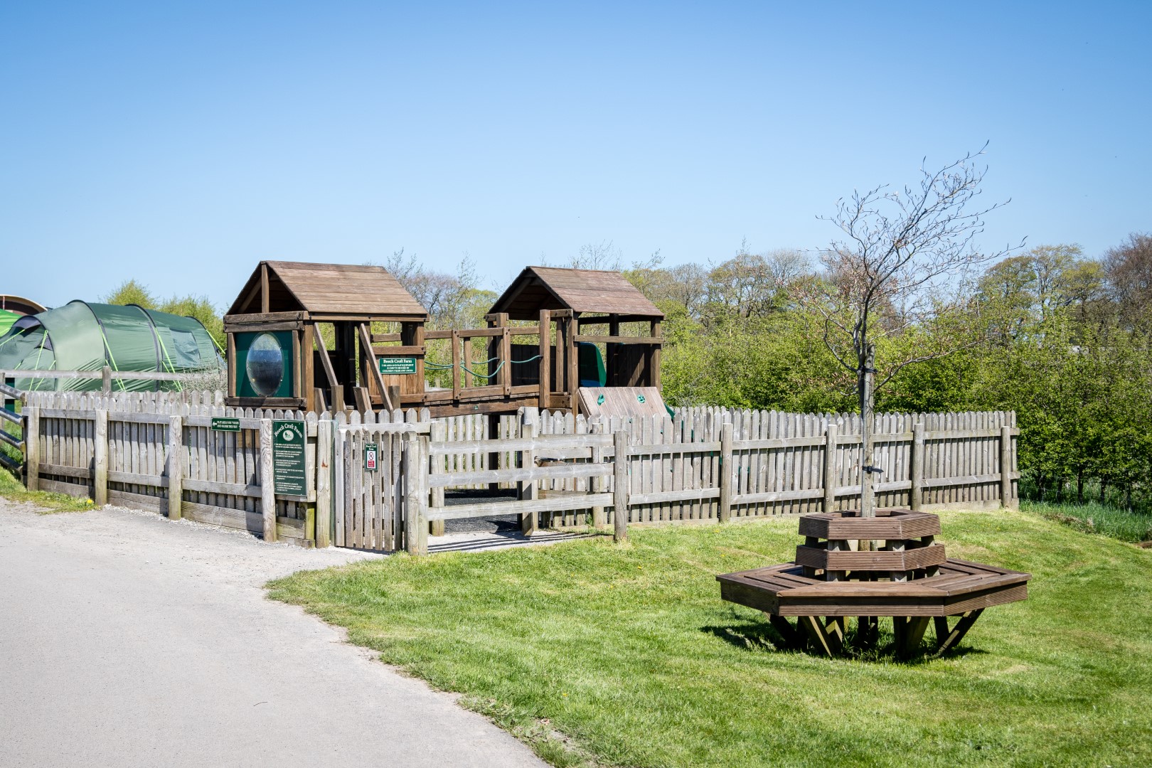 Wooden playground enclosed by a fence.