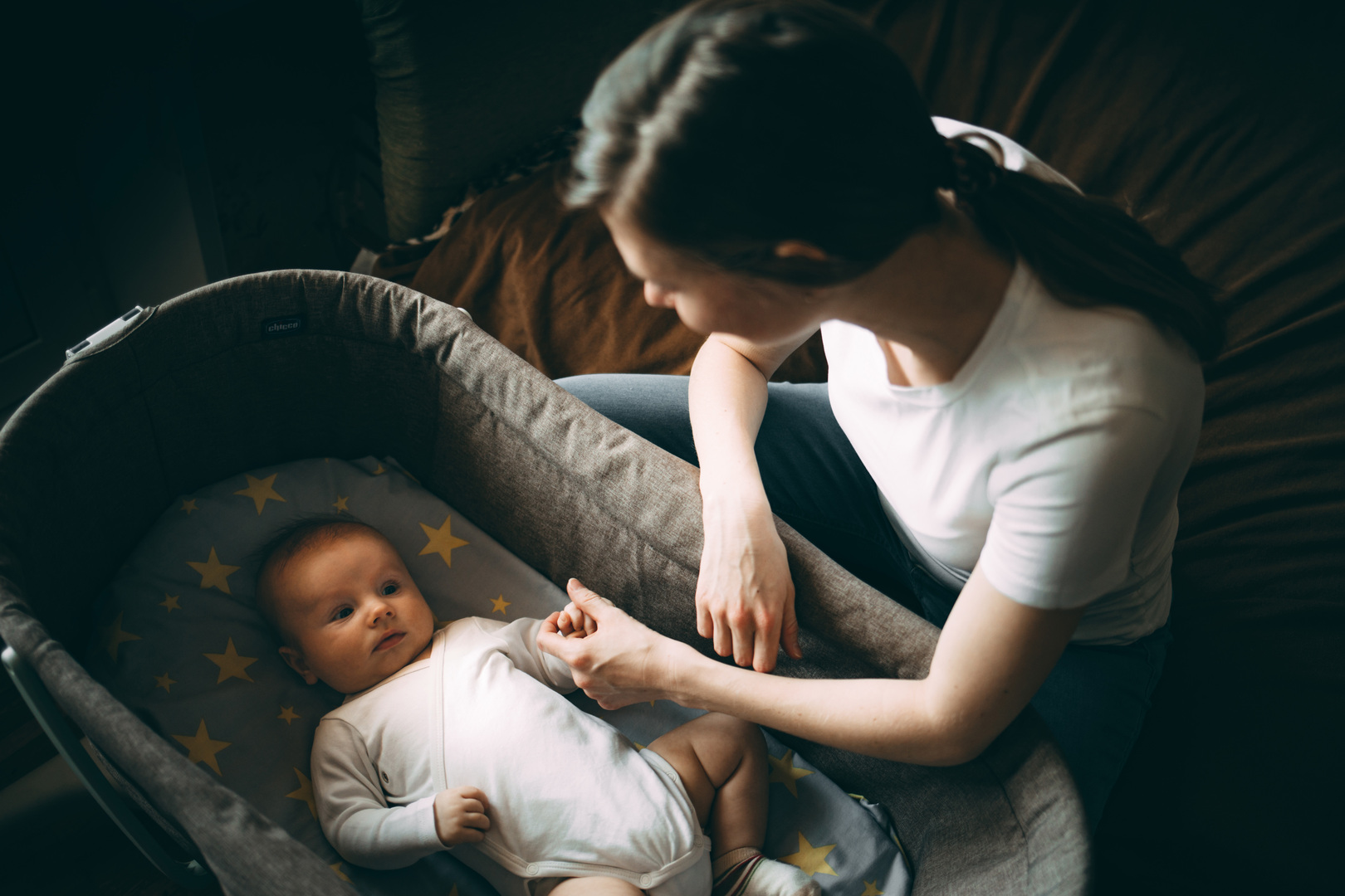 Woman holding her baby's hand in a crib.