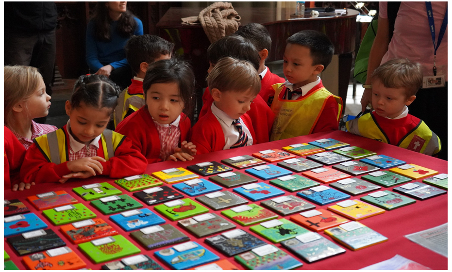 a group of children are looking at a table full of colorful tiles