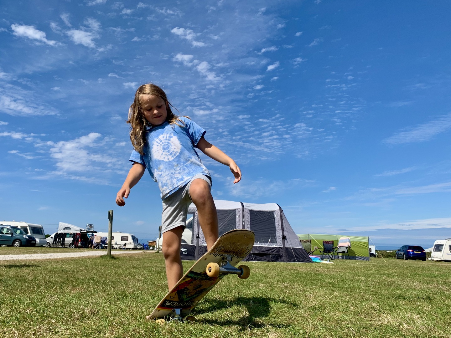 Child skateboarding at a campsite.